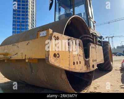 Straßenreparatur, Verdichter legt Asphalt. Schwere Spezialmaschinen. Asphaltfertiger in Betrieb. Seitenansicht. Nahaufnahme. Stockfoto