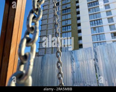 Eisenketten im Hintergrund eines Neuhauses auf einer Baustelle während des Baus von Industriegebäuden. Stockfoto