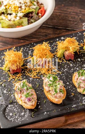 Bruschetta mit Meeresfrüchten mit asiatischen Aromen auf einem Steinschneidbrett Stockfoto