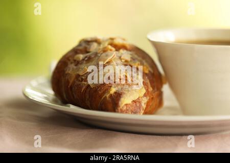 Ein Mandelcroissant und eine Tasse Kaffee Stockfoto