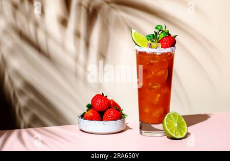 Paloma Cocktailgetränk mit Silbertequila, Grapefruit- und Limettensaft, frischen Erdbeeren, Minze und Eis im Glas mit Salzrand. Beigefarbener rosafarbener Hintergrund., Stockfoto