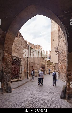 Menschen auf der Ponte di Castelvecchio oder Castelvecchio Brücke, die durch den Bogen vom Castelvecchio Museum, Verona Italien, aus gesehen werden Stockfoto