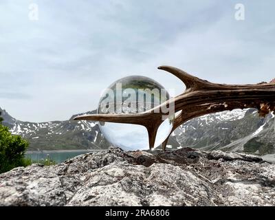 Röhrengeweih neben Linsenkugel, Kristallkugel, mit Reflexionen des Luenersee (Lünersee, Montafon, Vorarlberg). Stockfoto