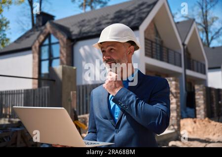 Architekt auf der Baustelle mit Schutzhelm, mit Laptop Stockfoto