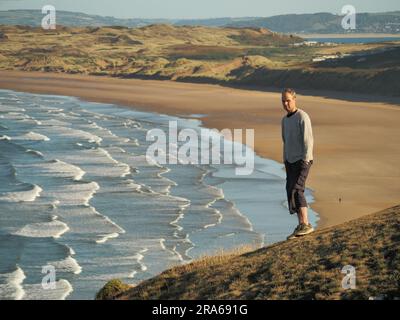 Mann mit Blick auf Rhossili Bay Beach, Gower Peninsula, Wales Stockfoto