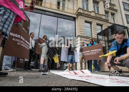 Berlin, Deutschland. 01. Juli 2023. In Berlin wurde der Hugo Boss Store, ein Leuchtfeuer der deutschen Luxusmode, am 1. Juli 2023 zur Bühne für einen Protest. Unter ukrainischen Flaggen versammelten sich Demonstranten vor dem Laden und verwandelten das Modezentrum in einen Ort politischer Ausdrucksfähigkeit und Widerstand. Die Botschaft der Demonstranten war klar und deutlich: "Hugo Boss, skandalös!" Es war ihr Rallying Cry, ein direkter Vorwurf für die Fortsetzung der Geschäftstätigkeit des Unternehmens in Russland trotz des anhaltenden Konflikts mit der Ukraine. "Keine Geschäfte mit Russland", sangen sie, ihre Stimmen hallten aus den Läden Stockfoto