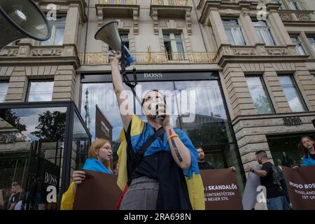 Berlin, Deutschland. 01. Juli 2023. In Berlin wurde der Hugo Boss Store, ein Leuchtfeuer der deutschen Luxusmode, am 1. Juli 2023 zur Bühne für einen Protest. Unter ukrainischen Flaggen versammelten sich Demonstranten vor dem Laden und verwandelten das Modezentrum in einen Ort politischer Ausdrucksfähigkeit und Widerstand. Die Botschaft der Demonstranten war klar und deutlich: "Hugo Boss, skandalös!" Es war ihr Rallying Cry, ein direkter Vorwurf für die Fortsetzung der Geschäftstätigkeit des Unternehmens in Russland trotz des anhaltenden Konflikts mit der Ukraine. "Keine Geschäfte mit Russland", sangen sie, ihre Stimmen hallten aus den Läden Stockfoto