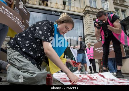 Berlin, Deutschland. 01. Juli 2023. In Berlin wurde der Hugo Boss Store, ein Leuchtfeuer der deutschen Luxusmode, am 1. Juli 2023 zur Bühne für einen Protest. Unter ukrainischen Flaggen versammelten sich Demonstranten vor dem Laden und verwandelten das Modezentrum in einen Ort politischer Ausdrucksfähigkeit und Widerstand. Die Botschaft der Demonstranten war klar und deutlich: "Hugo Boss, skandalös!" Es war ihr Rallying Cry, ein direkter Vorwurf für die Fortsetzung der Geschäftstätigkeit des Unternehmens in Russland trotz des anhaltenden Konflikts mit der Ukraine. "Keine Geschäfte mit Russland", sangen sie, ihre Stimmen hallten aus den Läden Stockfoto