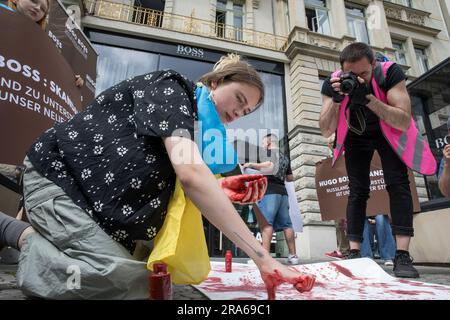 Berlin, Deutschland. 01. Juli 2023. In Berlin wurde der Hugo Boss Store, ein Leuchtfeuer der deutschen Luxusmode, am 1. Juli 2023 zur Bühne für einen Protest. Unter ukrainischen Flaggen versammelten sich Demonstranten vor dem Laden und verwandelten das Modezentrum in einen Ort politischer Ausdrucksfähigkeit und Widerstand. Die Botschaft der Demonstranten war klar und deutlich: "Hugo Boss, skandalös!" Es war ihr Rallying Cry, ein direkter Vorwurf für die Fortsetzung der Geschäftstätigkeit des Unternehmens in Russland trotz des anhaltenden Konflikts mit der Ukraine. "Keine Geschäfte mit Russland", sangen sie, ihre Stimmen hallten aus den Läden Stockfoto