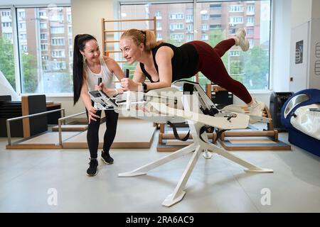 Frau beherrscht einen Virtual-Reality-Simulator unter Aufsicht des Trainers Stockfoto