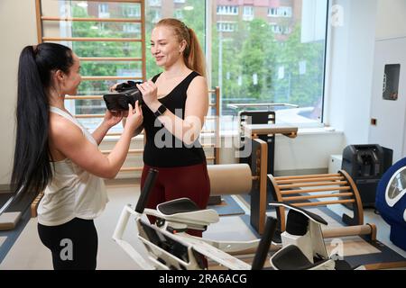 Mitarbeiter der Fitnessklinik geben einem Kunden ein Virtual-Reality-Headset Stockfoto