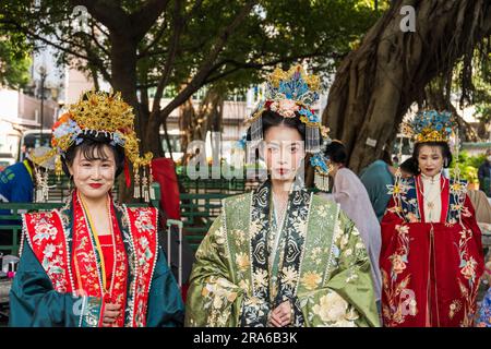 Hongkong, China -- 11. März 2023. Drei chinesische Frauen in einem Park, die traditionelle Hochzeitskleidung tragen. Stockfoto