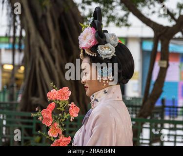 Hongkong, China -- 11. März 2023. Eine Chinesin in einem rosa Hochzeitskleid hält rosa Blumen in der Hand. Stockfoto