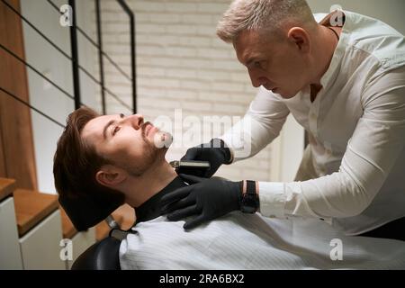 Der Friseur rasiert seine Kunden mit einem Spezialwerkzeug Stockfoto
