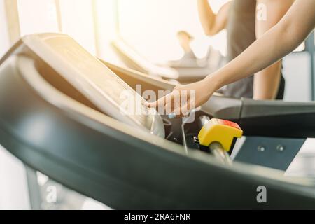 Gesundes Fitnessil, das im Laufband-Sportclub läuft, mit dem Nahfinger Geschwindigkeit und Steigleistung im Bedienpult einstellen. Stockfoto