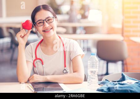 Glücklicher Kardio-Arzt-Student mit rotem Herz-Zeichen für Liebesheilung mit Menschen-Konzept. Stockfoto