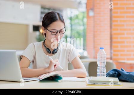 Teenager-Rezension einer asiatischen Universität, die ein Buch liest, Bildung, einen intelligenten Lebensstil für Schüler lernt. Stockfoto