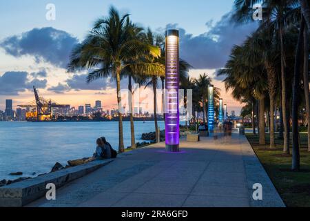 Miami Beach, Florida, USA. Blick auf den beleuchteten Fußweg im South Pointe Park, South Beach, Dämmerung, Downtown Miami im Hintergrund. Stockfoto