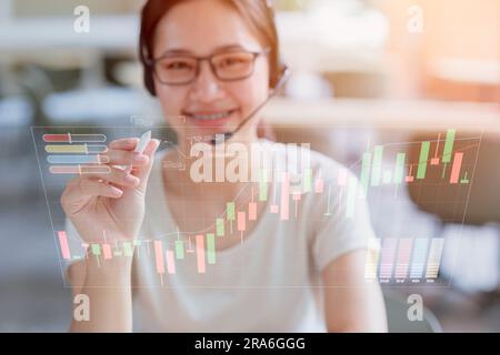 Glückliche Geschäftsfrau, die mit moderner Technologie lächelt Holo-Grafiken überlagern die Reihenfolge der Handelsaktienkarten. Stockfoto