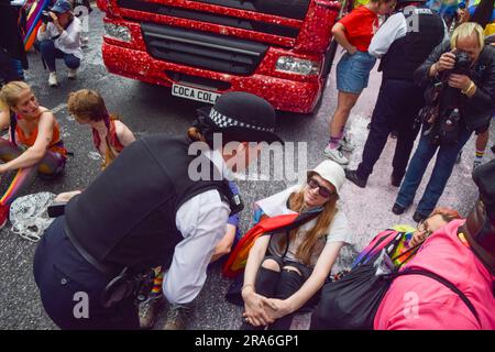 London, England, Großbritannien. 1. Juli 2023. Ein Polizist versucht, die Demonstranten davon zu überzeugen, von der Straße wegzugehen. Just Stop Oil-Aktivisten aus der LGBTQ-Gemeinde haben rosa Farbe besprüht und die Pride in London Parade blockiert, indem sie vor einem Coca-Cola-Truck saßen, der an der Parade teilnahm, um gegen Pride zu protestieren, der mit Industrien zusammenarbeitet, die mit der Klimakrise in Verbindung stehen, und um gegen Coca-Cola zu protestieren, Gilt als der weltweit größte Verursacher von Plastik. (Kreditbild: © Vuk Valcic/ZUMA Press Wire) NUR REDAKTIONELLE VERWENDUNG! Nicht für den kommerziellen GEBRAUCH! Stockfoto