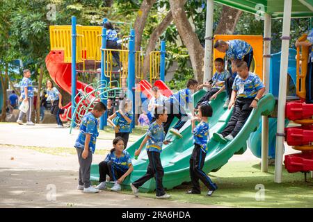 Bangkok, Thailand - Juni 26 2023: Gruppe von Kindern niedlich verspielt glücklich genießen Sie mit Spielplatzausstattung im Schulpark draußen. Stockfoto