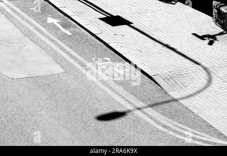 Schatten und Straßenmarkierungen auf der Straße der Stadt, dem Radweg und dem Gehweg in Schwarz und Weiß, von oben Stockfoto