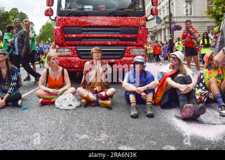 London, Großbritannien. 01. Juli 2023. Während der Demonstration sitzen Demonstranten und blockieren die Straße. Just Stop Oil-Aktivisten aus der LGBTQ-Gemeinde haben rosa Farbe besprüht und die Pride in London Parade blockiert, indem sie vor einem Coca-Cola-Truck saßen, der an der Parade teilnahm, um gegen Pride zu protestieren, der mit Industrien zusammenarbeitet, die mit der Klimakrise in Verbindung stehen, und um gegen Coca-Cola zu protestieren, Gilt als der weltweit größte Verursacher von Plastik. Kredit: SOPA Images Limited/Alamy Live News Stockfoto