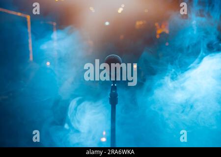 Studiomikrofon in Neonlichtern. Tonaufnahmegerät. Mikrofon und Bühnenbeleuchtung. Konzert- und Musikkonzept. Stockfoto