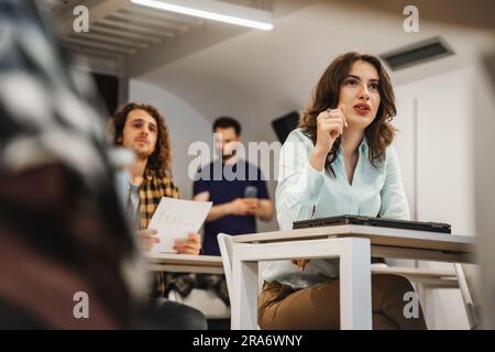 Atemberaubende brünette Mitarbeiterin, die während einer Präsentation im Klassenzimmer Fragen stellt Stockfoto