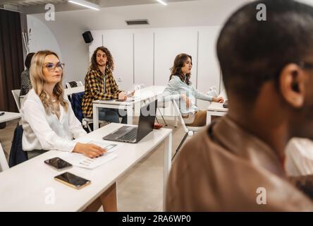 Multiethnische, generationenübergreifende Gruppe von Studenten, die nach Abschluss des Kurses einen Test machen Stockfoto