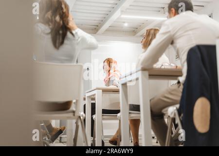 Ginger, weibliche Mitarbeiterin mit Hijab, die ihrem Kollegen zuhört. Multikulturelle Geschäftskollegen diskutieren Projekte und neue Ideen bei Modern Stockfoto