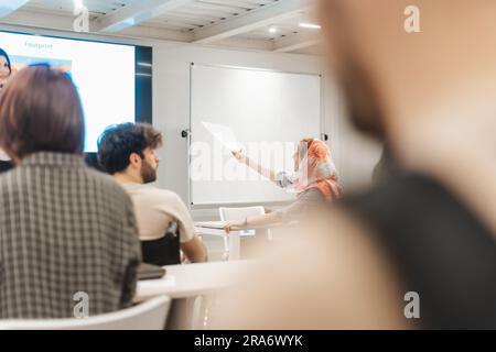 Generationenübergreifende, multiethnische Geschäftsleute, die in einem modernen Konferenzraum zusammenarbeiten. Rothaarige, weibliche Mitarbeiterin trägt Hijab, der Dokumente übergibt Stockfoto