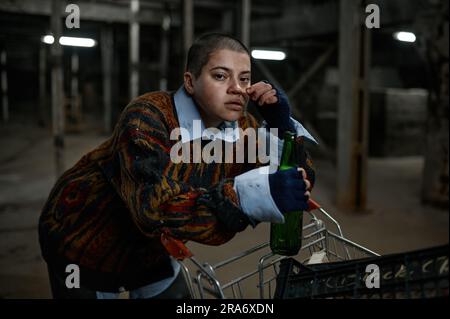 Porträt einer unglücklichen betrunkenen Immigrantin oder Bettler, die Bier trinkt Stockfoto