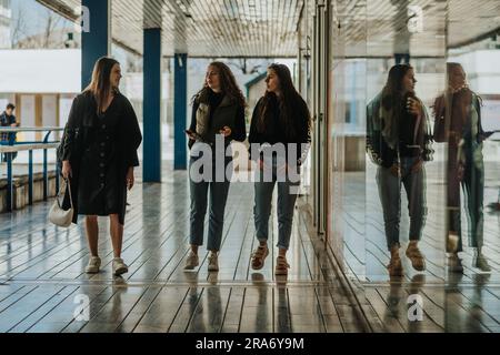 Zwei reizende Mädchen fragten ihre Freundin (links), warum sie sich überlegte, nicht in die Boutique zu gehen Stockfoto