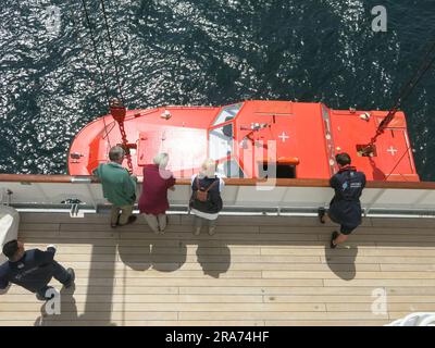 Ein Besatzungsmitglied des Kreuzfahrtschiffs „Heritage Adventurer“ beobachtet vom Deck aus, wie einer der Beißer für einen Passagiertransfer ins Wasser abgesenkt wird. Stockfoto