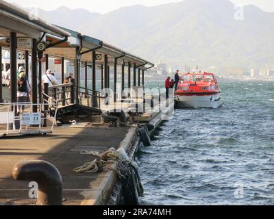 Am Pier am Fährhafen Miyajima liegt ein Tender vor, damit die Passagiere zurück zu ihrem Kreuzfahrtschiff fahren können. Stockfoto