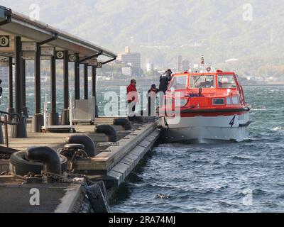 Am Pier am Fährhafen Miyajima liegt ein Tender vor, damit die Passagiere zurück zu ihrem Kreuzfahrtschiff fahren können. Stockfoto