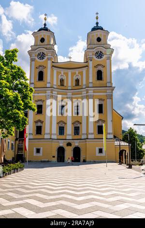 Mondsee, Oberösterreich – AT – 7. Juni 2023 Außenansicht der gelben barocken Fassadenkirche, Basilika St. Michael, einem ehemaligen Kloster. Stockfoto