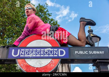 1. Juli 2023 - Ein Mann besteigt am Pride Day 2023 im Zentrum von London, Trafalgar Square, ein Schild der Londoner U-Bahn Stockfoto