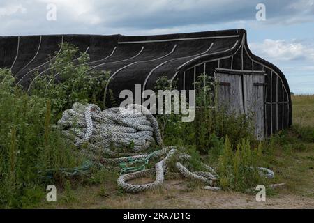 Upturned, ausgefallenes Boot, das als Schuppen am Hafen umfunktioniert wurde Stockfoto