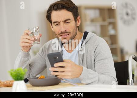 Ein Gelegenheitsmann schaut beim Mittagessen auf das Smartphone Stockfoto