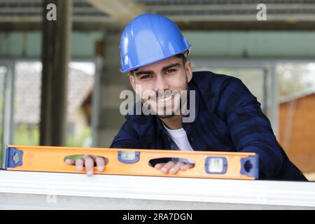 Mann, der eine Wasserwaage benutzt, um eine Wand zu plotchen Stockfoto