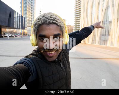 Selfie-Porträt eines jungen afroamerikanischen Mannes in Sportkleidung mit Ohrhörern in einer Stadt Stockfoto