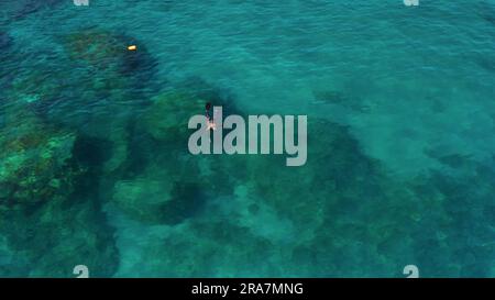 Albisola, Italien - 13. Juni 2021: Taucher schwimmt und taucht in der Nähe der Küste des ligurischen Meeres in transparentem, flachem, türkisfarbenem Wasser. Draufsicht oben Stockfoto