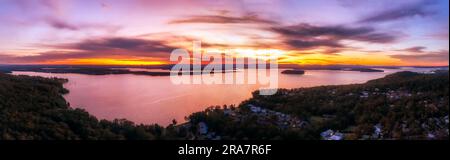 Roter farbenfroher Sonnenuntergang über dem Lake Macquarie in Australien - breites Panoramablick von Murrays Beach Town Ufer. Stockfoto