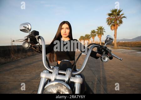 Schöne junge Frau, die an sonnigen Tagen Motorrad fährt Stockfoto