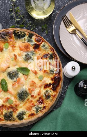 Köstliche hausgemachte Lachs-Quiche mit Brokkoli auf schwarzem Tisch, flach liegend Stockfoto