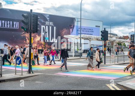 Die Menschen überqueren die Straße über einen farbenfrohen Fußgängerübergang, der in den Regenbogenfarben gemalt ist, die Synonyme für die LGBQT-Gemeinde in London sind Stockfoto