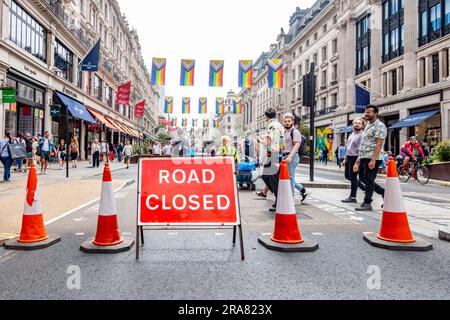 Die Regent Street ist wegen der alljährlichen London Pride-Veranstaltung geschlossen, wobei ein rotes Schild und Verkehrskegel den Weg versperren. Farbenfrohe Flaggen Hand über. Stockfoto