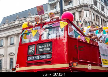 Teilnehmer der jährlichen London Pride Veranstaltung im Juli 2023 reisen in einem Doppeldeckerbus mit offenem Oberdeck. Stockfoto
